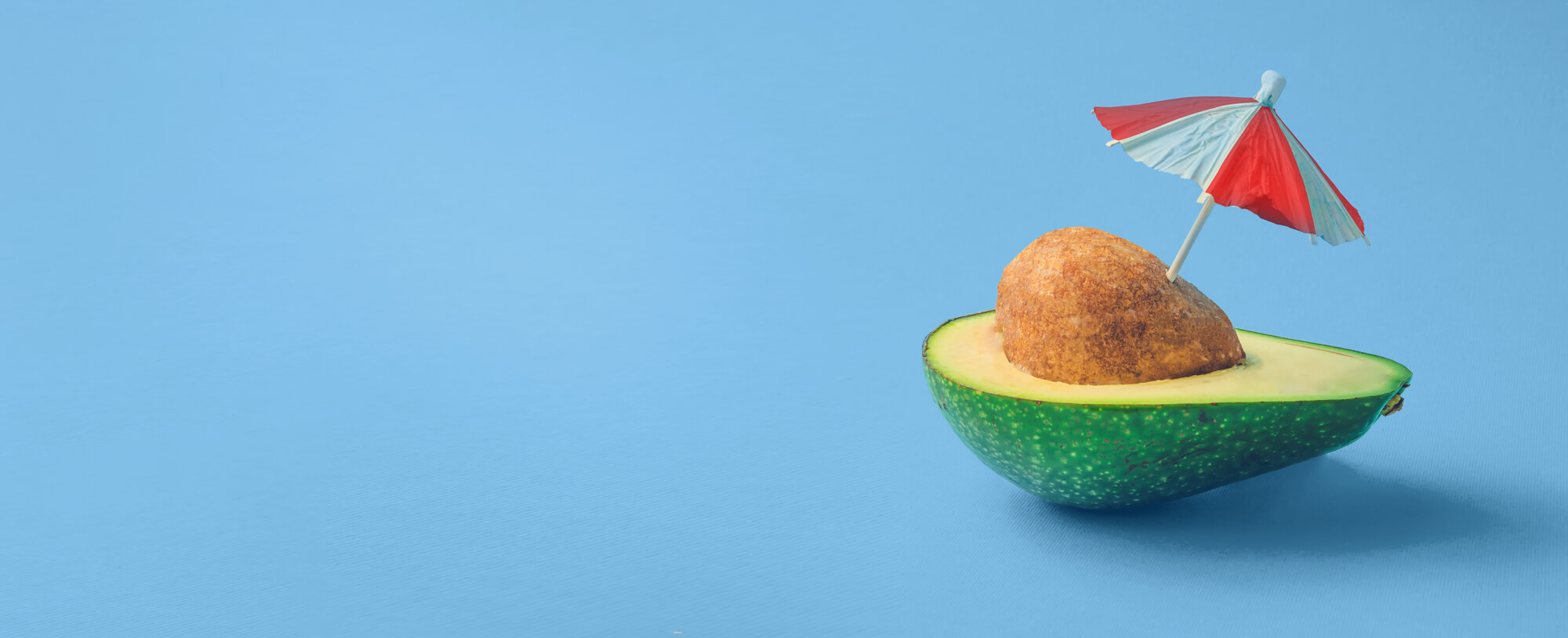 avocado with umbrella on blue background